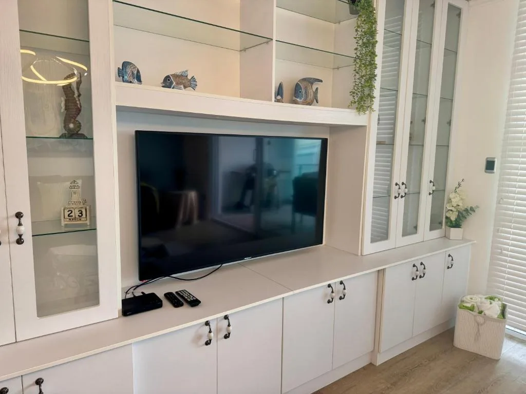 Modern white entertainment unit with flat-screen TV and coastal decor accents