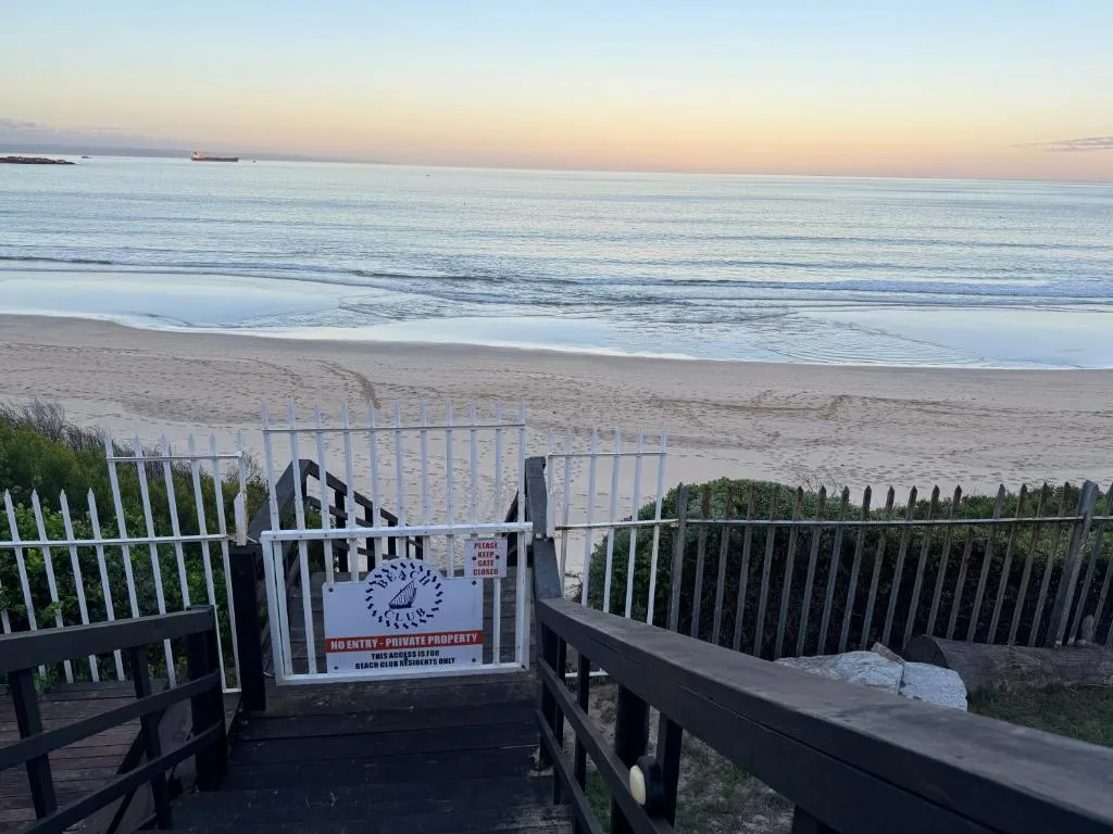 Serene coastal view of sandy beach and calm ocean at sunset from property