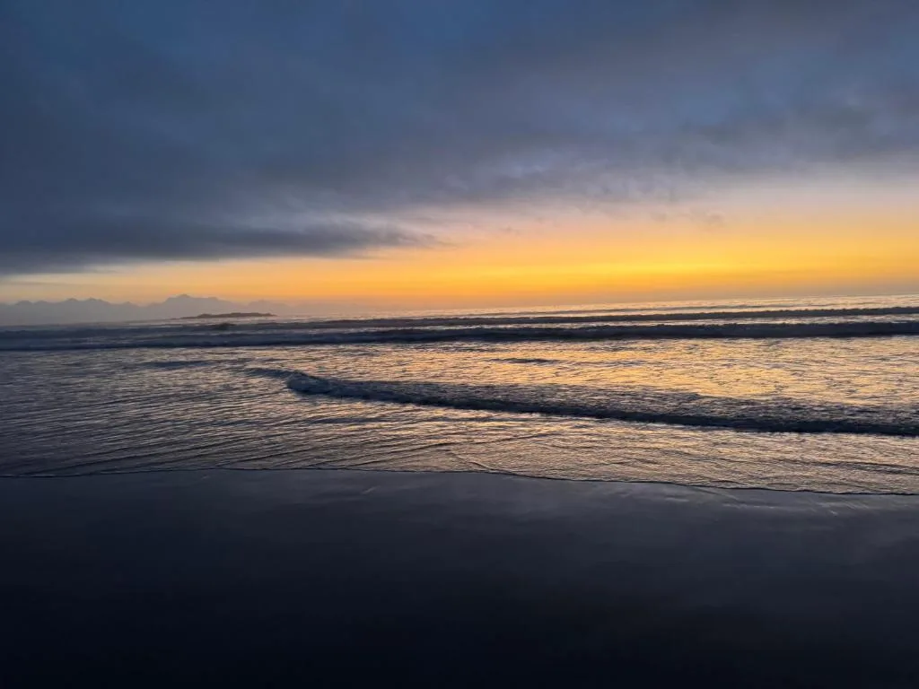 Golden sunset over the ocean with waves and distant mountains