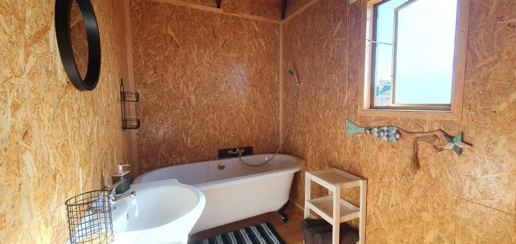 Spacious bathroom with freestanding white bathtub and cork walls