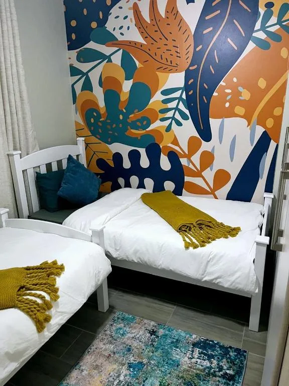 Twin beds with white frames and colorful botanical wall mural backdrop