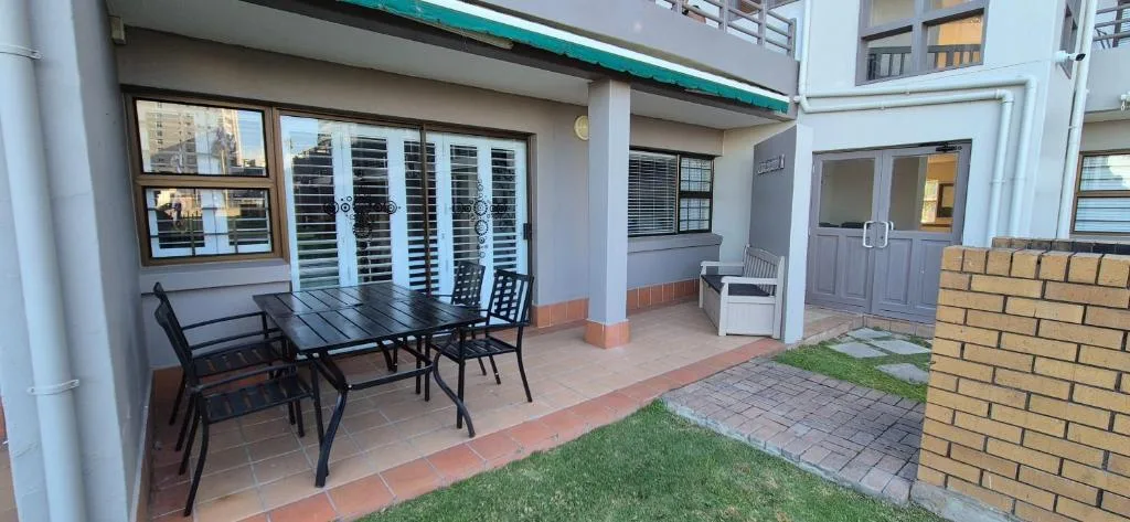 Covered patio with dining table and chairs overlooking garden area