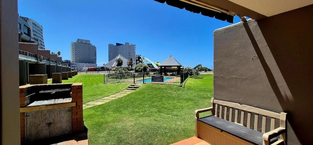Shaded patio with bench overlooking green lawn and coastal town buildings