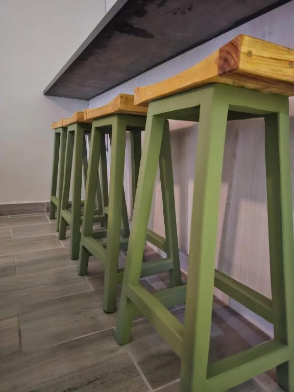 Row of green wooden bar stools with natural wood tops indoors