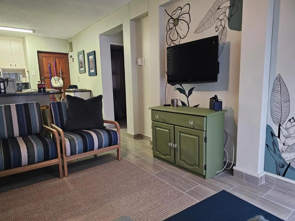 Spacious living room with striped armchair, wall-mounted TV, and green console table