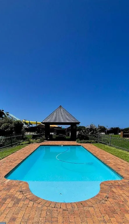 Bright blue swimming pool with brick surround and modern building