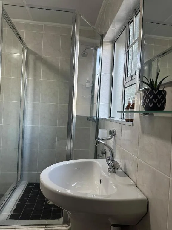 Modern bathroom with walk-in shower, white sink vanity, and mirror shelving