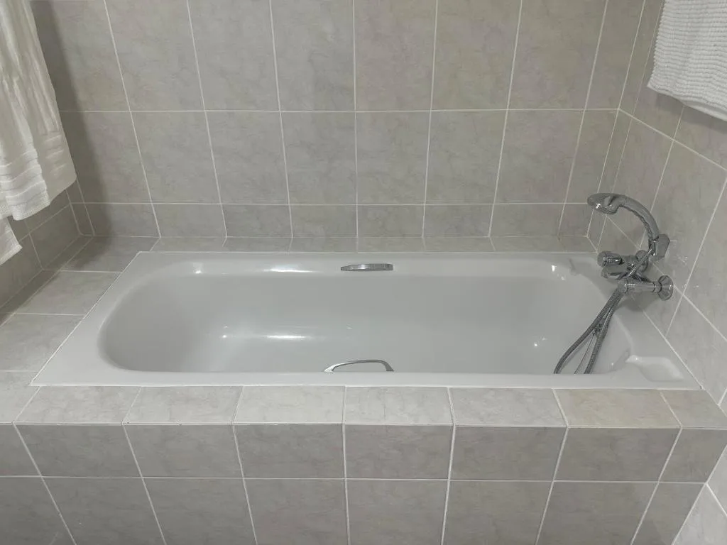Clean white bathtub with chrome faucet and tiled surround