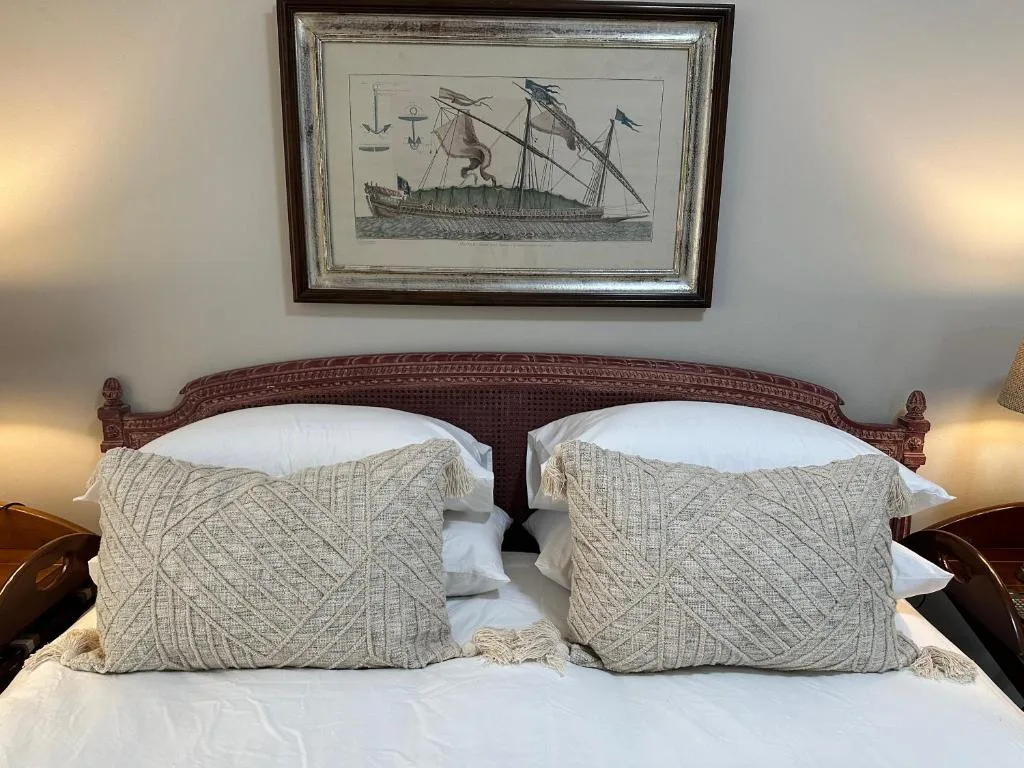 Double bed with patterned cushions and nautical ship artwork above headboard