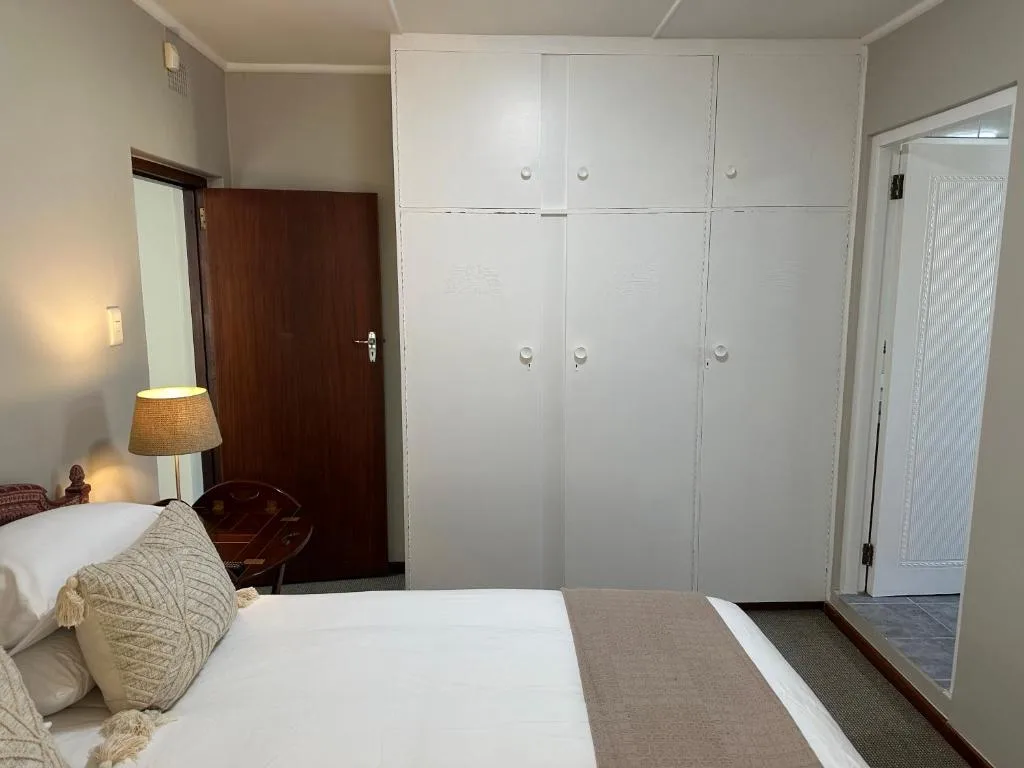 Bedroom with double bed, white wardrobes, and bedside lamp