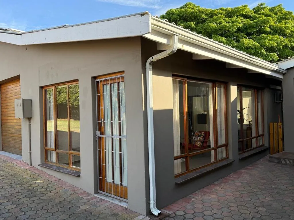 Modern white cottage exterior with wooden-framed glass doors and brick patio