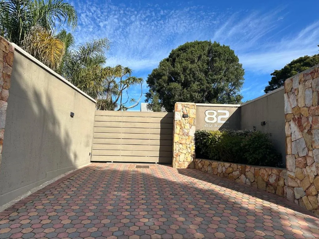 Modern driveway entrance with closed gate and stone pillars