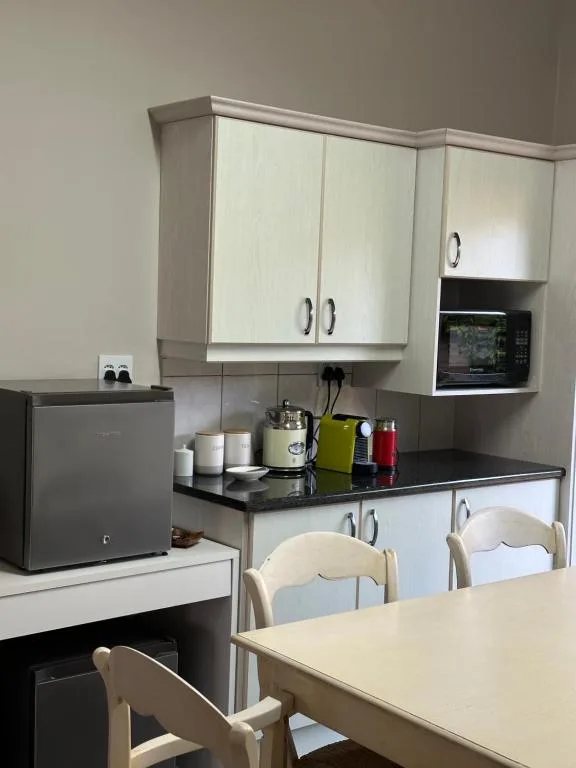 Modern kitchen with white cabinetry, black countertop, and integrated microwave oven