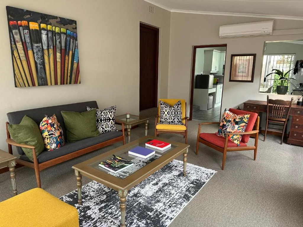 Colorful living room with sofa, armchairs, coffee table, and artwork