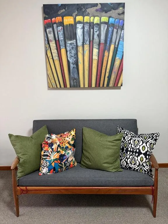 Mid-century modern sofa with colorful cushions and artistic brush painting above