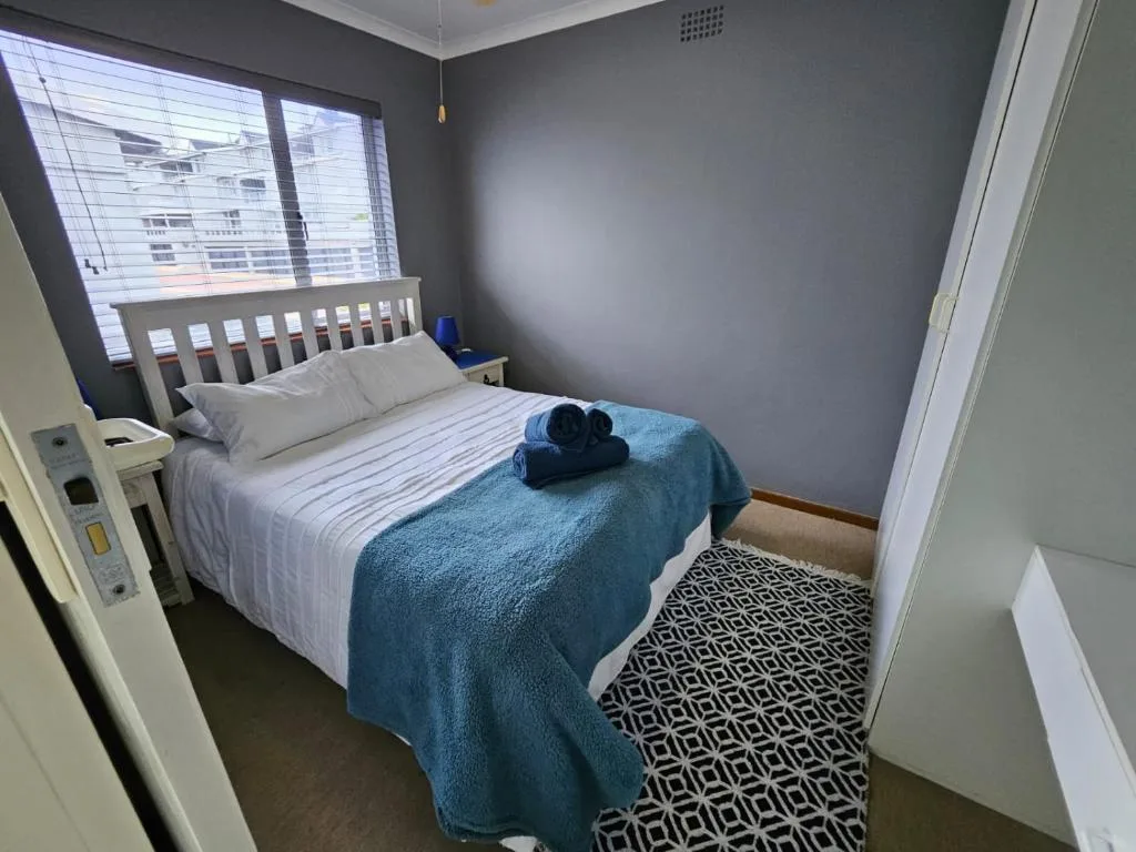 Modern bedroom with double bed, blue bedding, and city view through window
