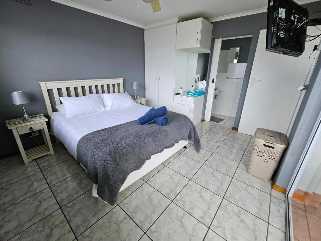 Spacious bedroom with queen bed, white wooden headboard, and en-suite bathroom access