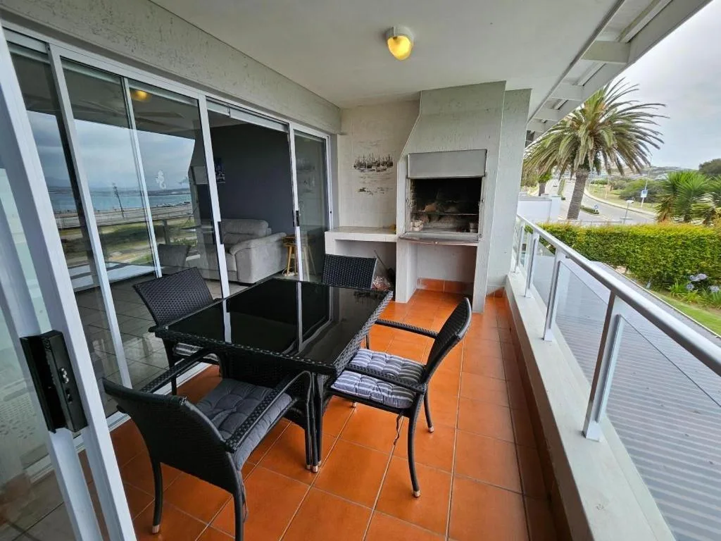 Oceanview balcony with dining table, loungers, and built-in fireplace