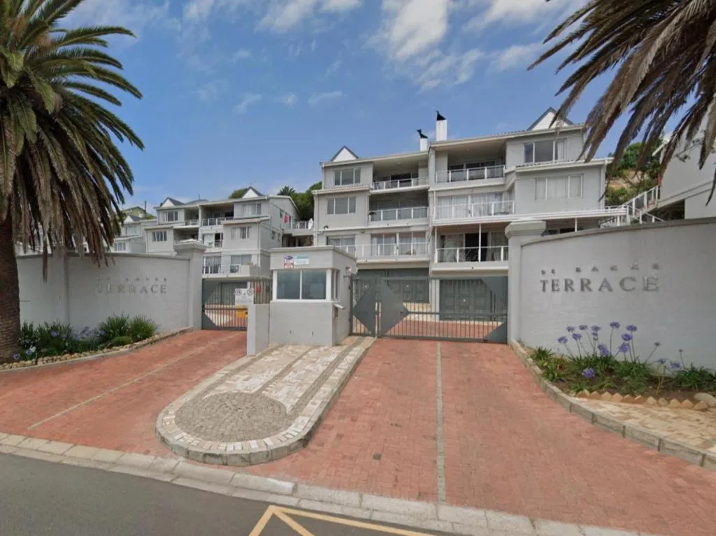 White apartment complex with palm trees and brick driveway entrance
