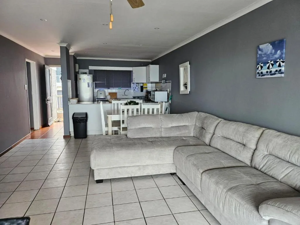 Open-plan living room with gray sectional sofa and kitchen visible beyond