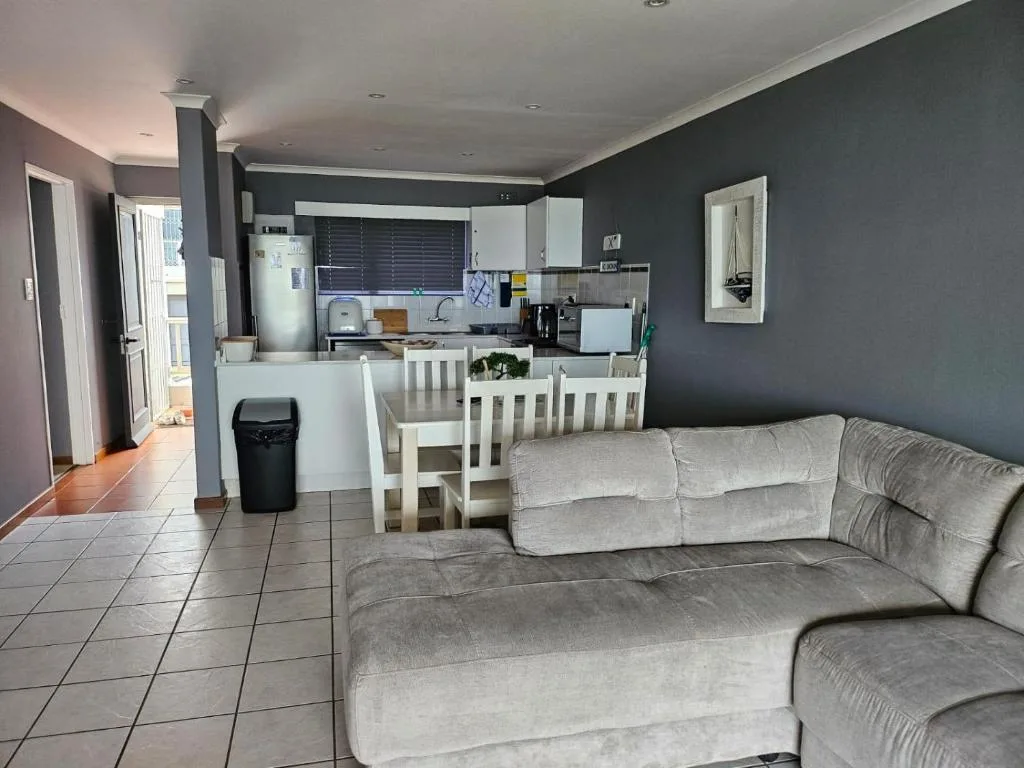 Open-plan lounge with grey sofa, dining area, and kitchen beyond