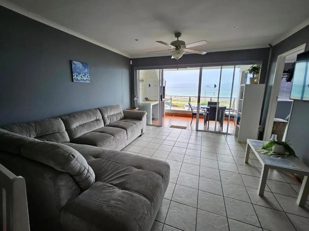 Spacious lounge with grey sofa and ocean view through glass doors