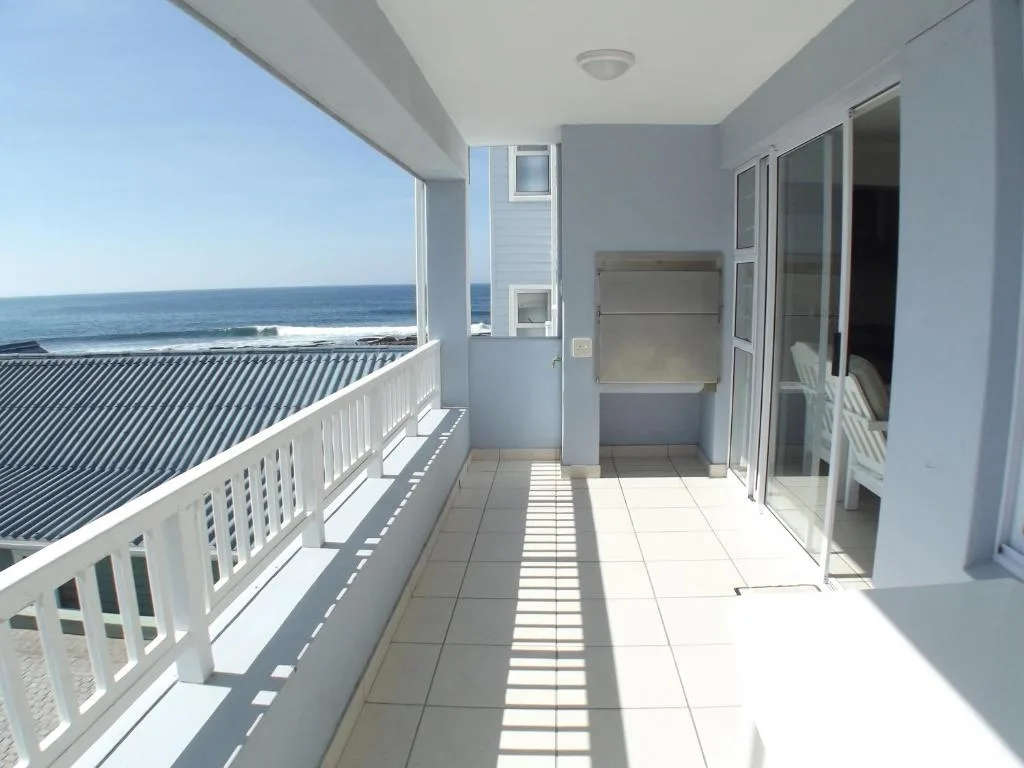 Oceanfront balcony with sea views, white railings, and tiled flooring