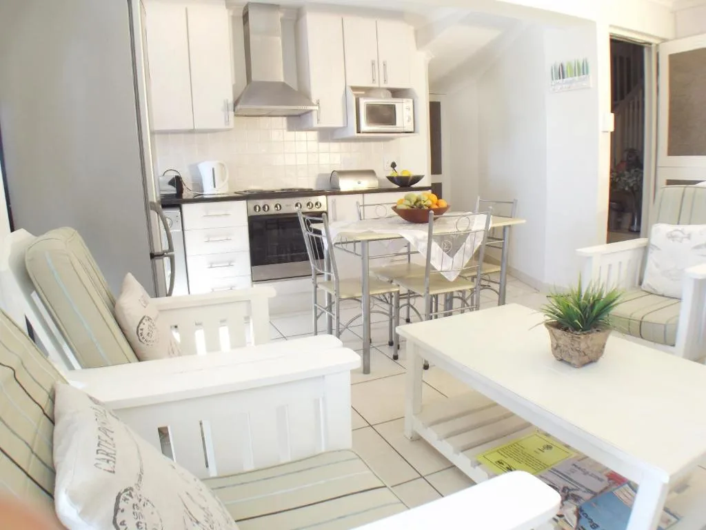 Open-plan kitchen with white cabinetry, stainless steel appliances, and dining area