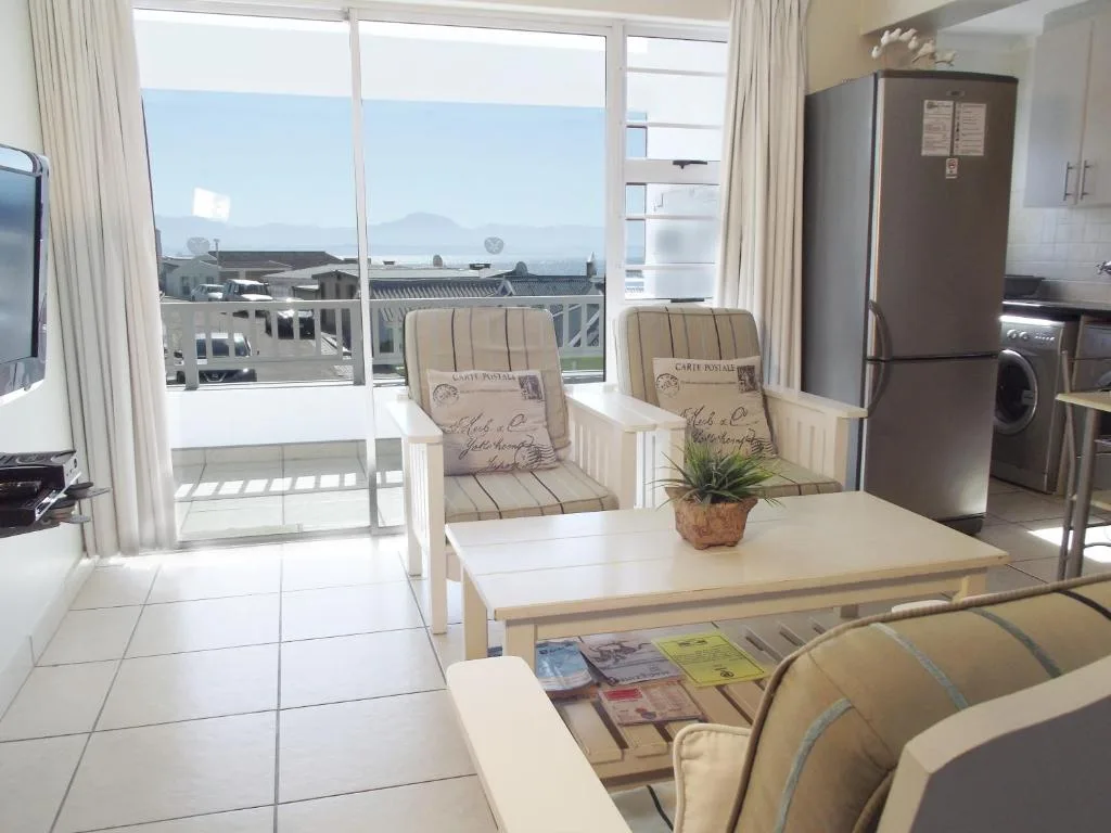 Open-plan lounge with seating, dining table, and mountain views through large windows