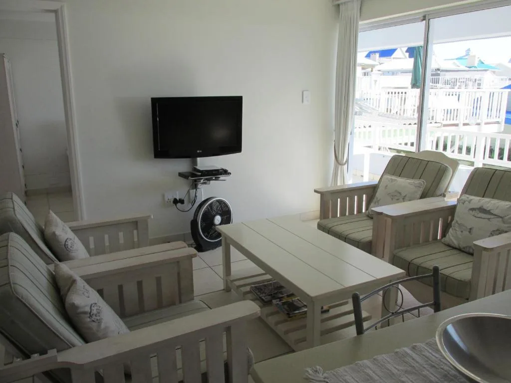 Bright living room with TV, comfortable seating, and coastal views through sliding doors