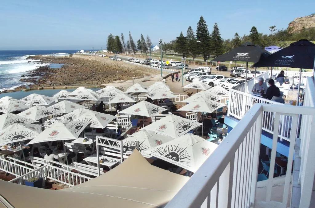 Coastal beach scene with umbrella-shaded seating and ocean vista beyond