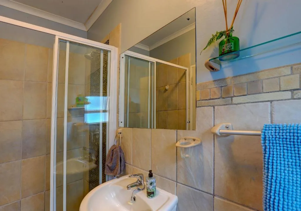 Modern bathroom with shower enclosure, vanity sink, and blue towel rack