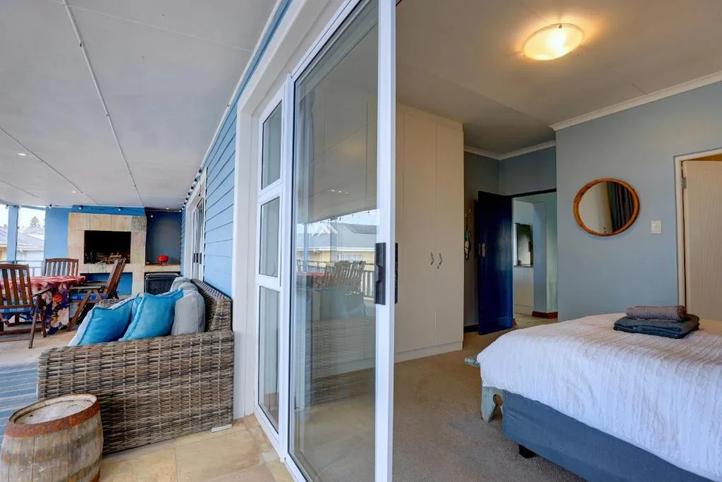 Bright bedroom with queen bed, ocean views through glass doors to deck