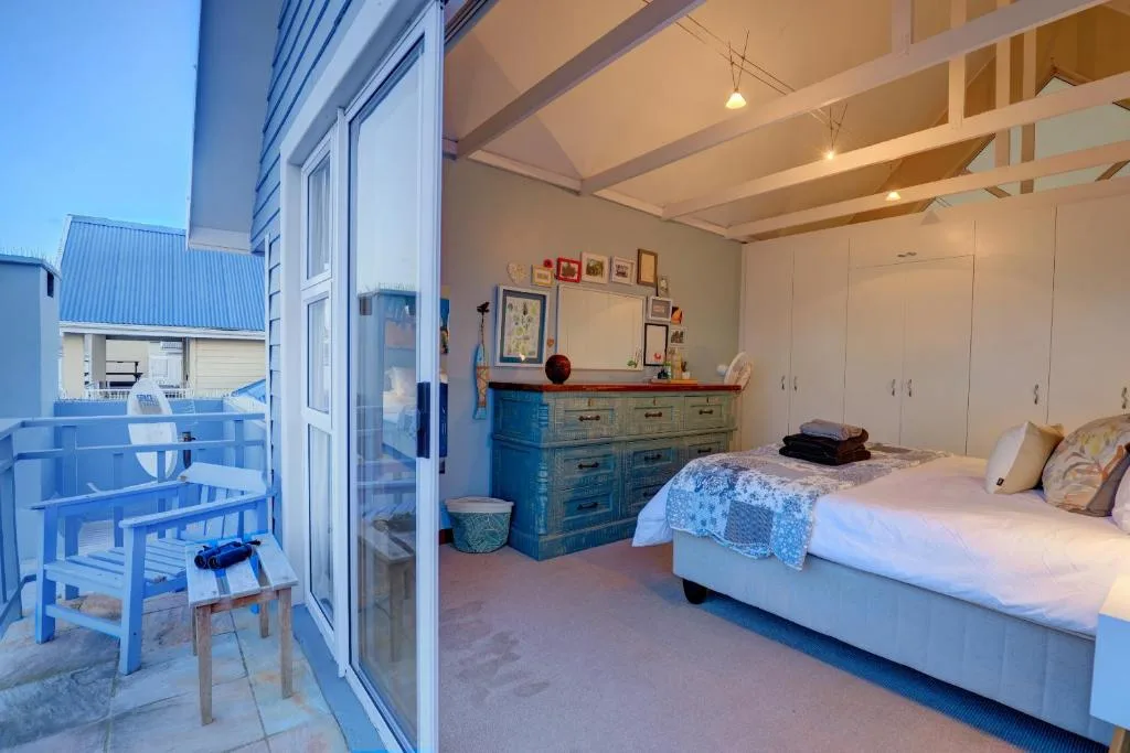 Bright bedroom with queen bed, blue dresser, and deck access overlooking gardens