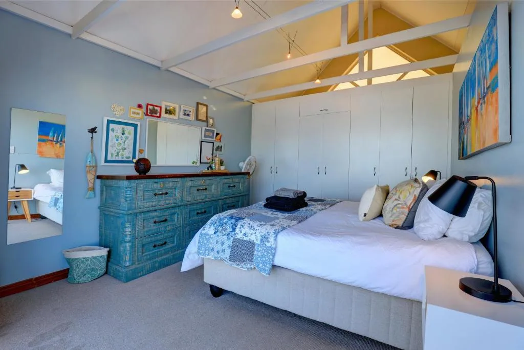 Bright bedroom with bed, turquoise dresser, and white built-in wardrobes