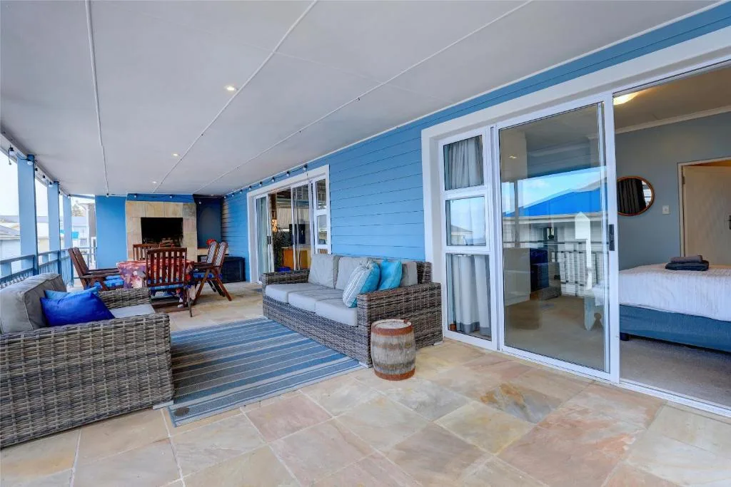 Covered outdoor deck with blue walls, wicker seating, and ocean views