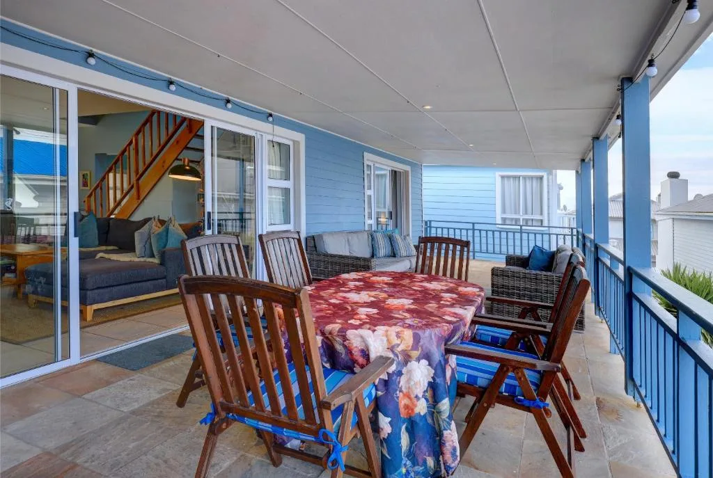 Covered deck with dining table, wooden chairs, and ocean views