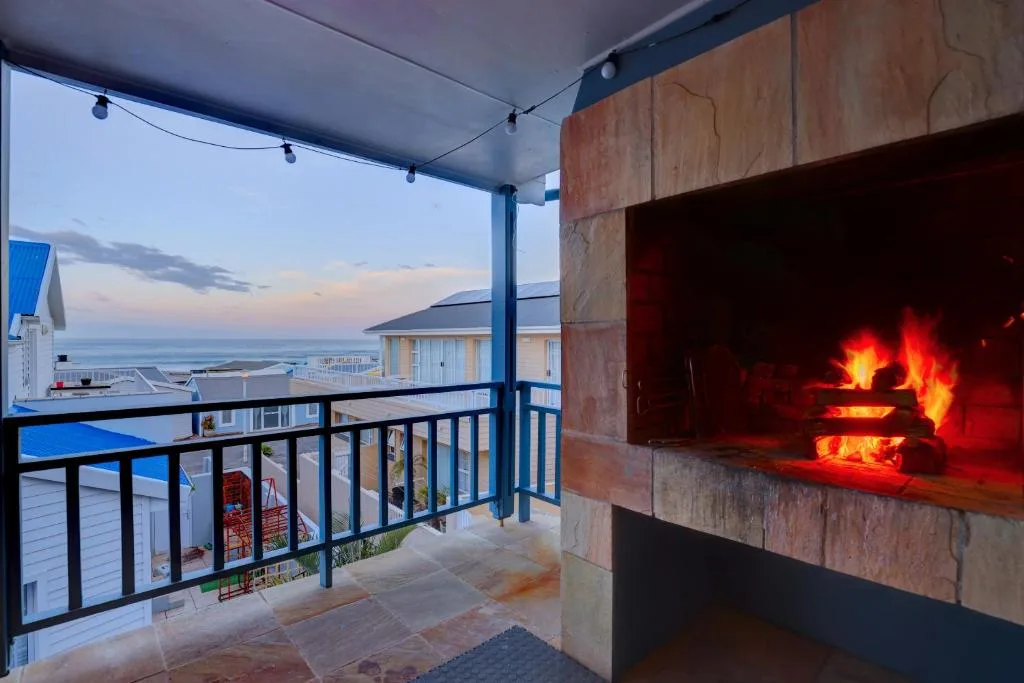 Covered ocean-view deck with fireplace and coastal sunset perspective