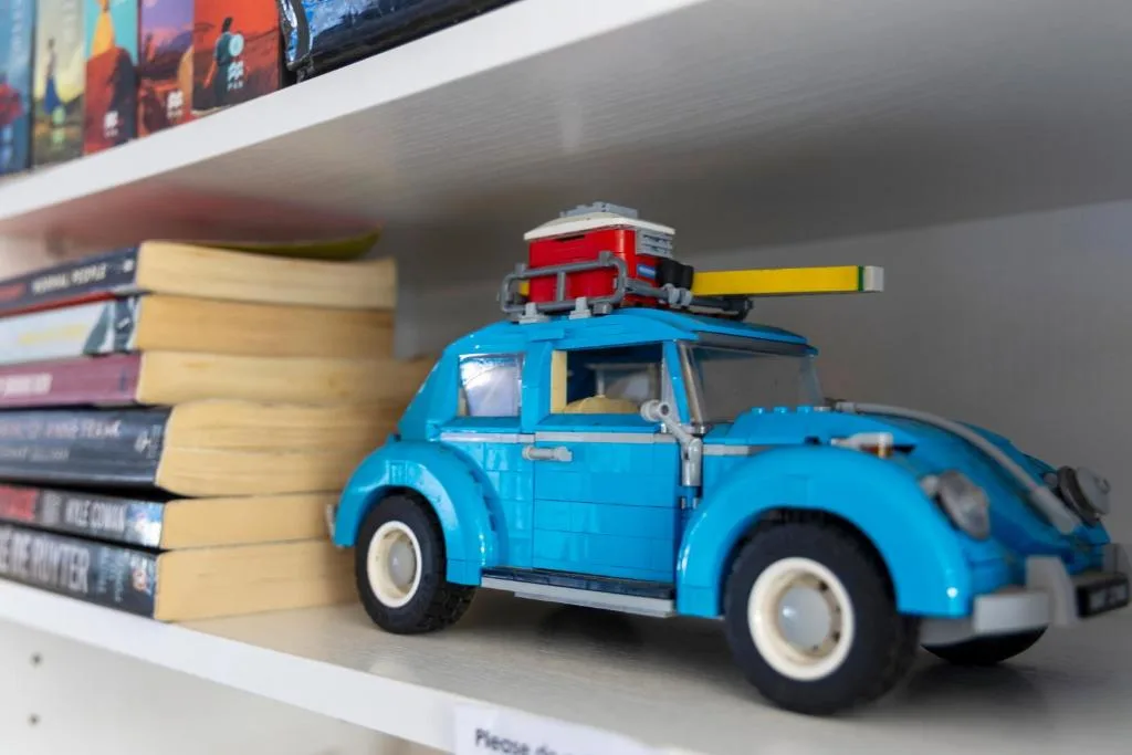 Decorative blue toy car with books on white shelf display