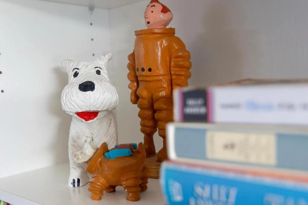 Colorful ceramic figurines and books on shelf, decorative home accent