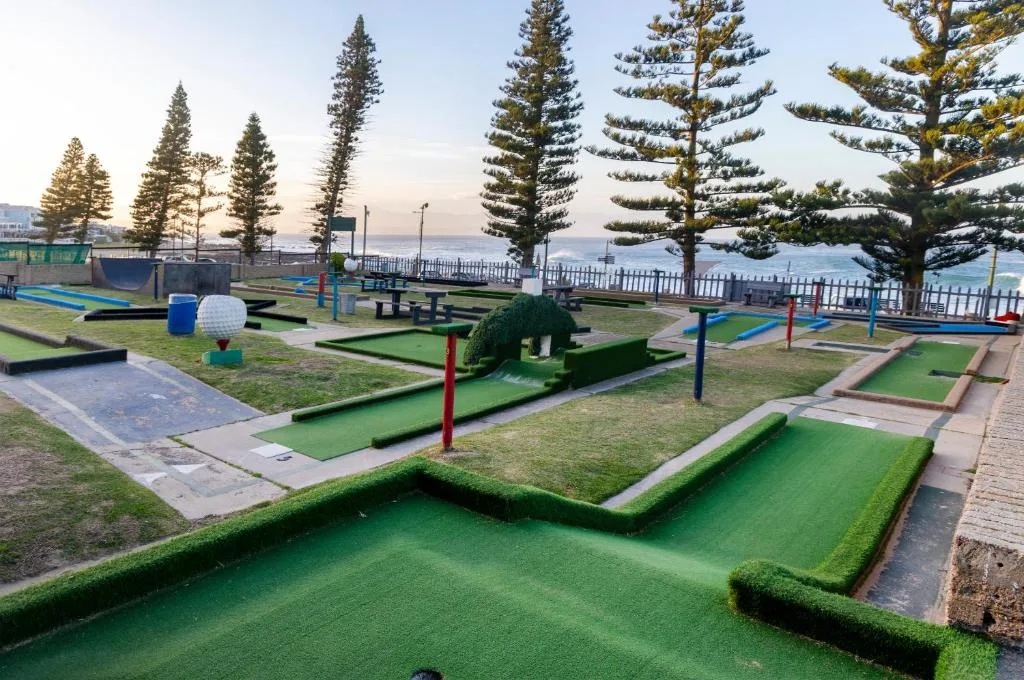 Miniature golf course with ocean view and pine trees in background
