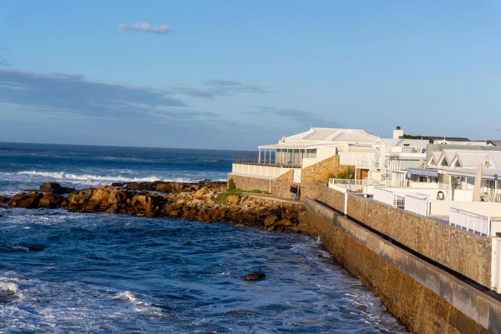 Cream and white beachfront apartment building perched on rocky coastline
