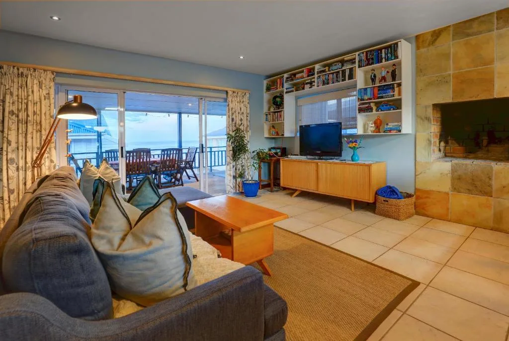 Spacious living room with sofa, TV, and ocean views through glass doors