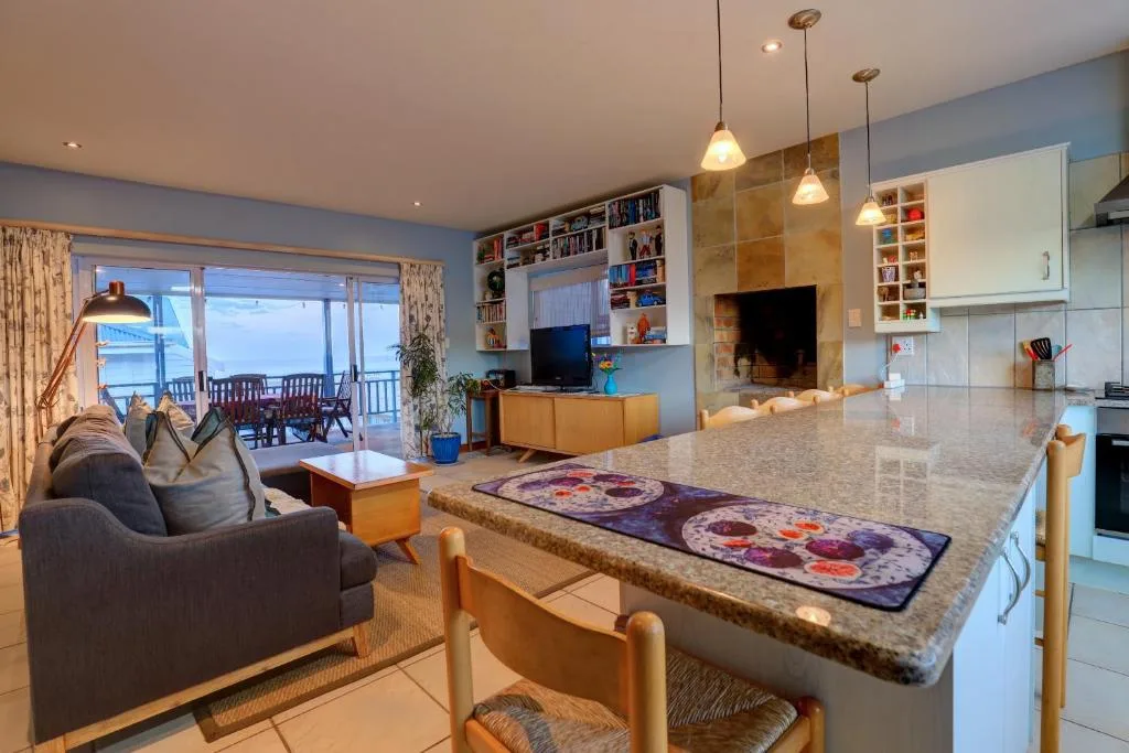 Open-plan lounge with fireplace, sofa, and ocean views through glass doors