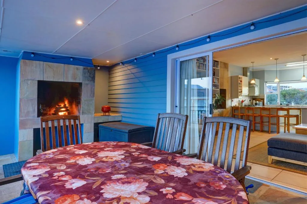 Open-plan lounge with fireplace, dining table, and kitchen visible beyond