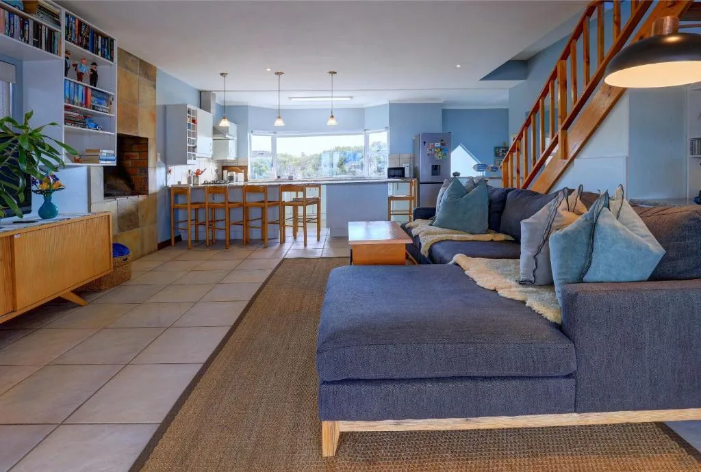 Open-plan lounge with blue upholstered sofa and kitchen visible beyond