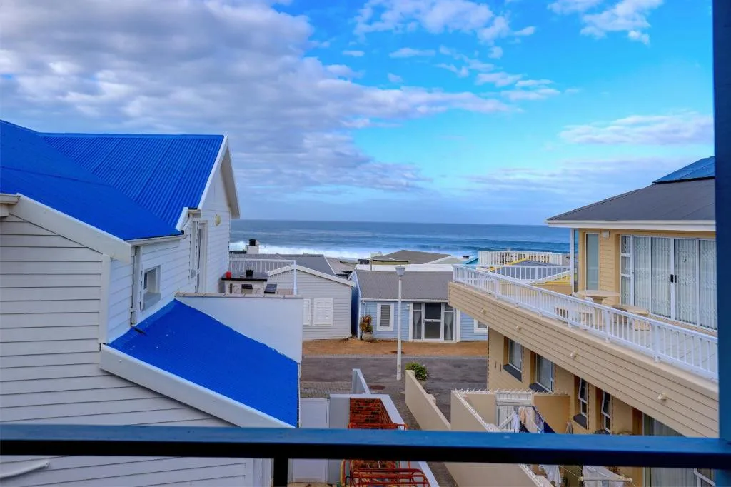 Ocean and beach view from elevated balcony overlooking coastal properties