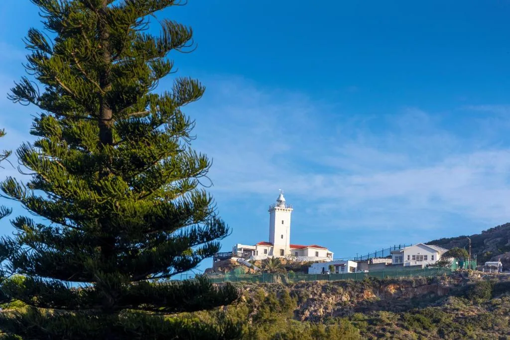 Iconic lighthouse on rocky coastal headland with clear blue sky