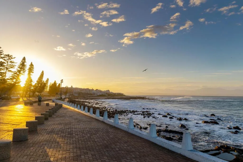 Sunset coastal promenade with rocky shoreline and golden ocean light