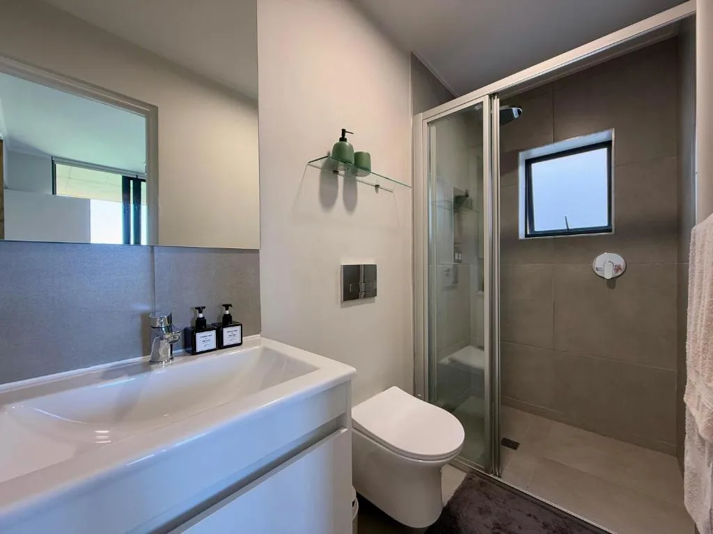 Modern bathroom with white vanity, toilet, and walk-in shower enclosure